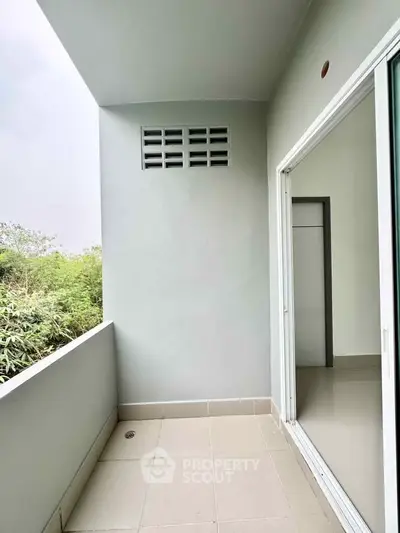 Spacious balcony with sliding glass door and serene greenery view, perfect for relaxation and outdoor enjoyment.