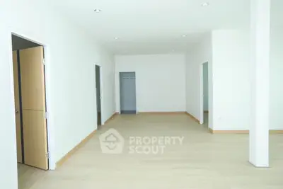 Spacious open-plan interior with light wood flooring and multiple doorways, ideal for customization.