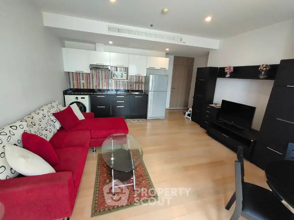 Modern living room with red sofa, open kitchen, and stylish decor in a contemporary apartment.