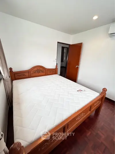 Spacious bedroom with elegant wooden bed frame and plush mattress, perfect for restful nights.