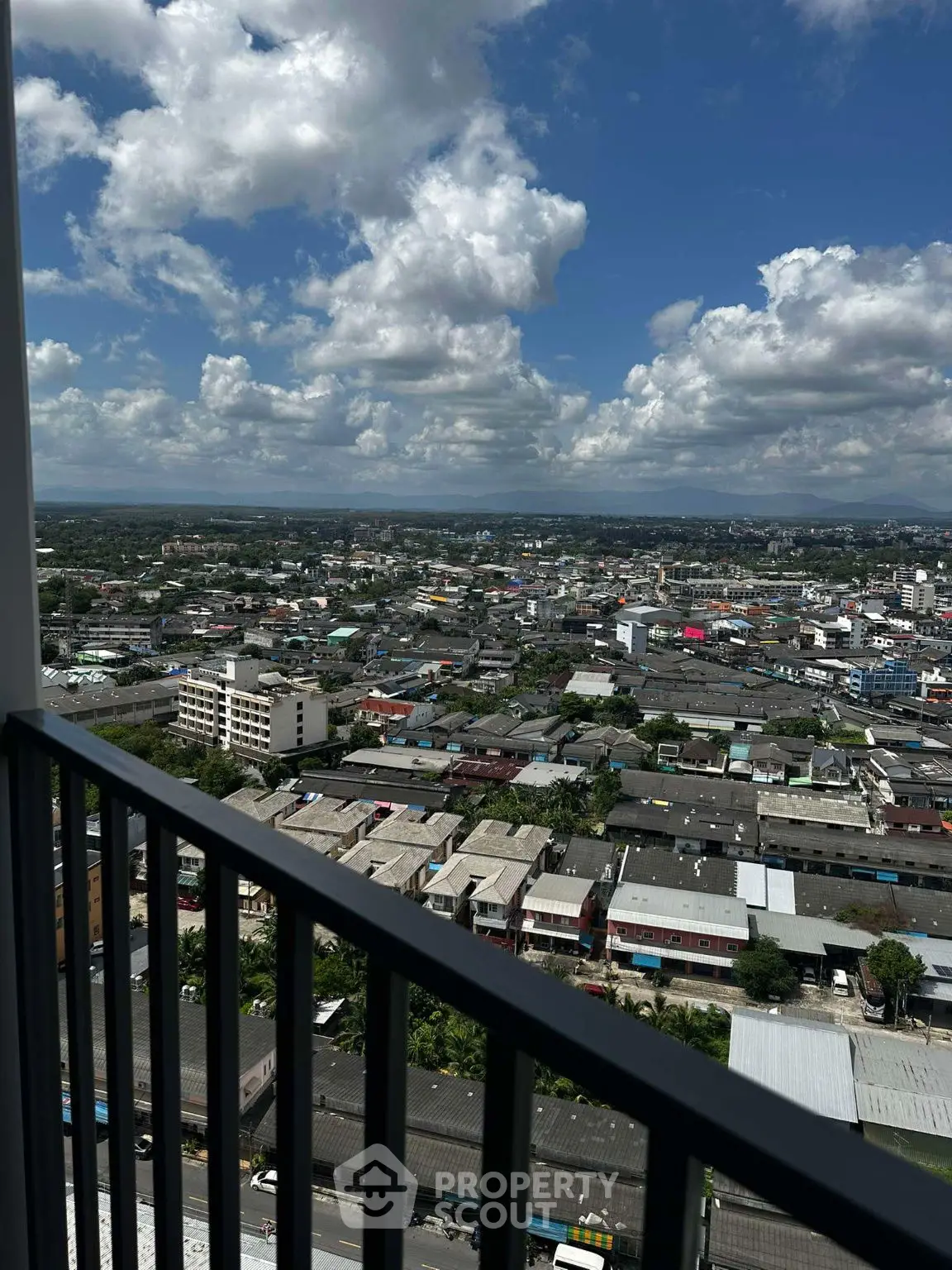 Stunning cityscape view from high-rise balcony with expansive skyline and clouds.