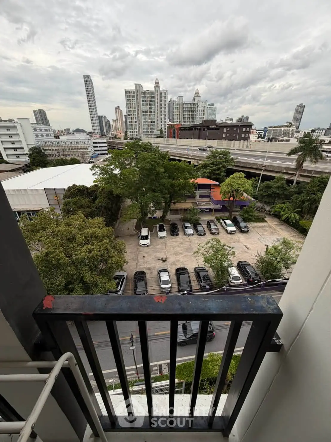 Urban cityscape view from a balcony overlooking parking area and skyline.