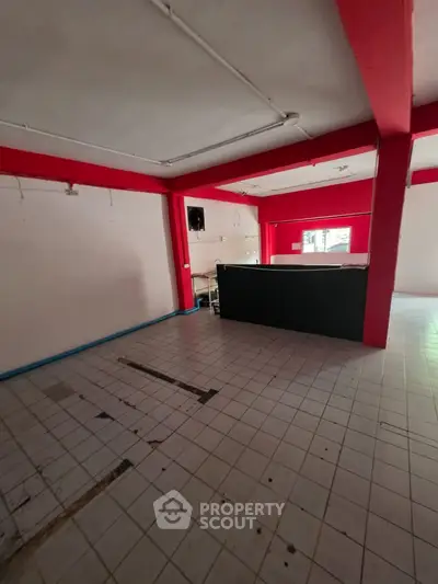 Spacious commercial property with tiled flooring and vibrant red accents, ideal for business setup.