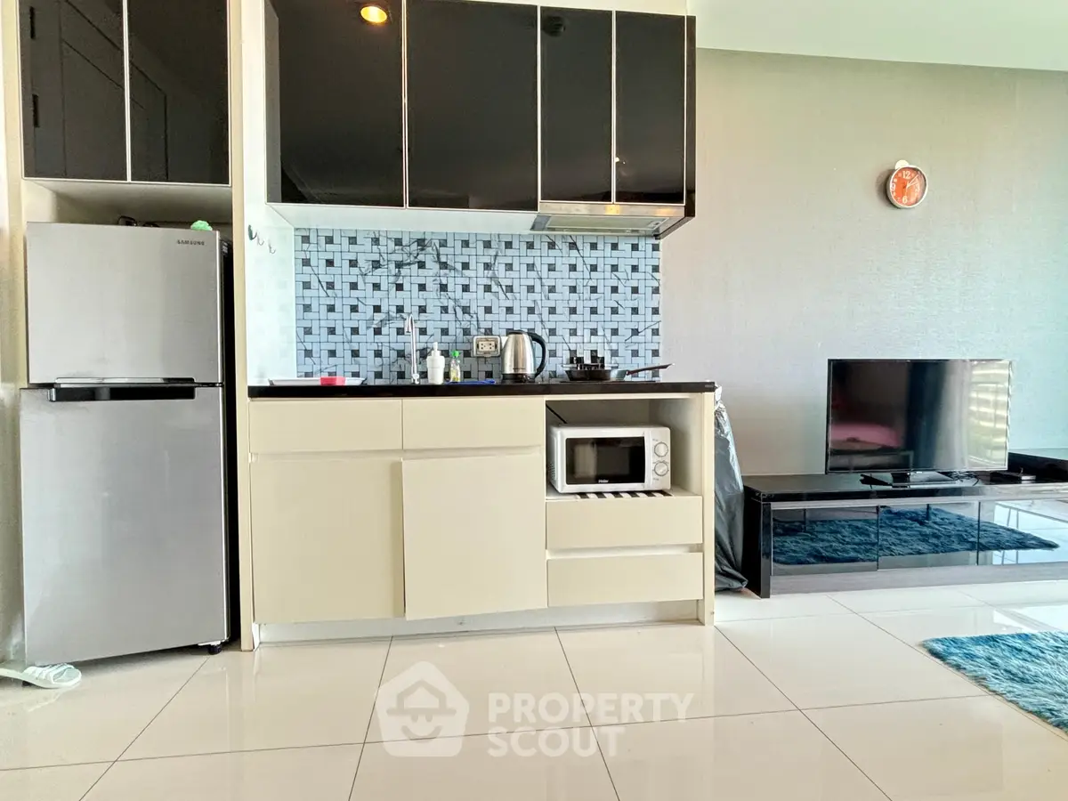 Modern kitchen with sleek cabinets, microwave, and fridge in stylish apartment.