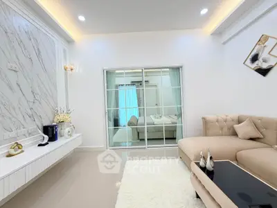 Elegant living room with modern decor and plush seating, featuring a stylish glass partition and chic lighting.