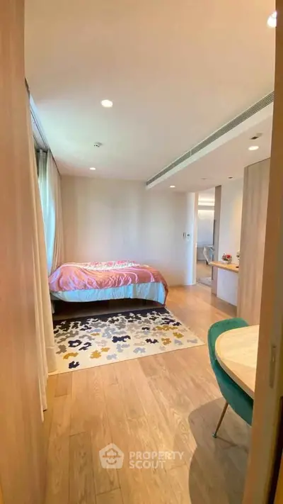 Cozy bedroom with modern decor and natural light, featuring a stylish rug and elegant furnishings.