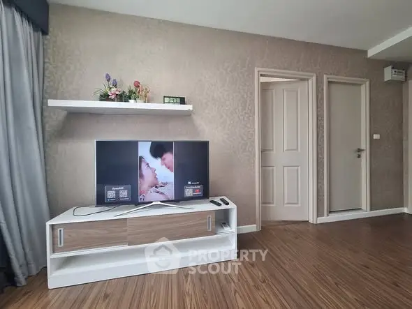 Modern living room with stylish TV stand and wall-mounted shelf, featuring elegant decor and wooden flooring.