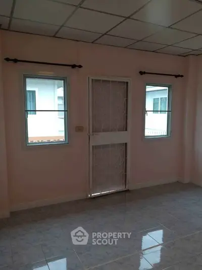 Spacious room with tiled floor and large windows, perfect for natural light.