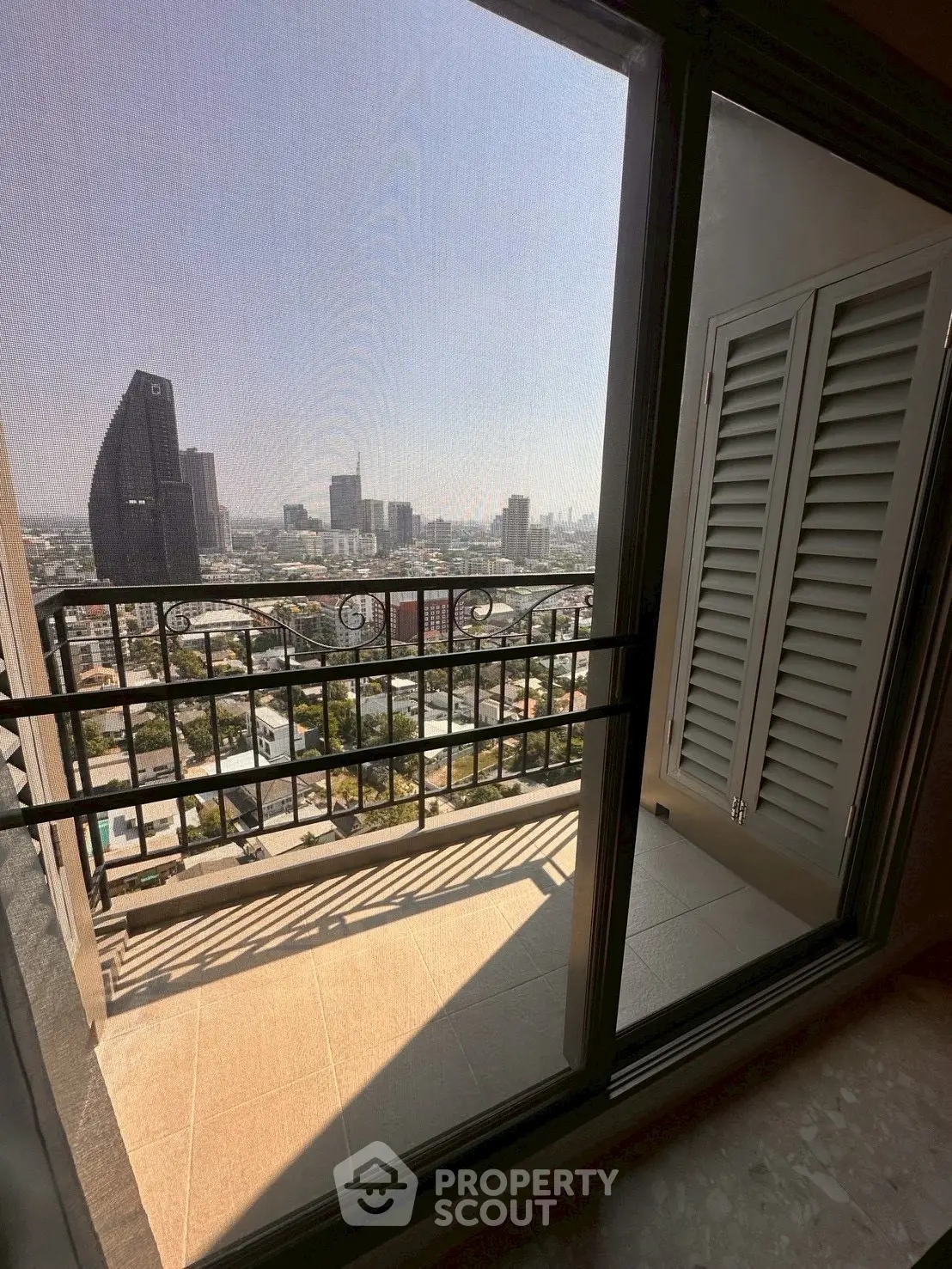 Stunning city view from a high-rise balcony with modern railing and glass doors.