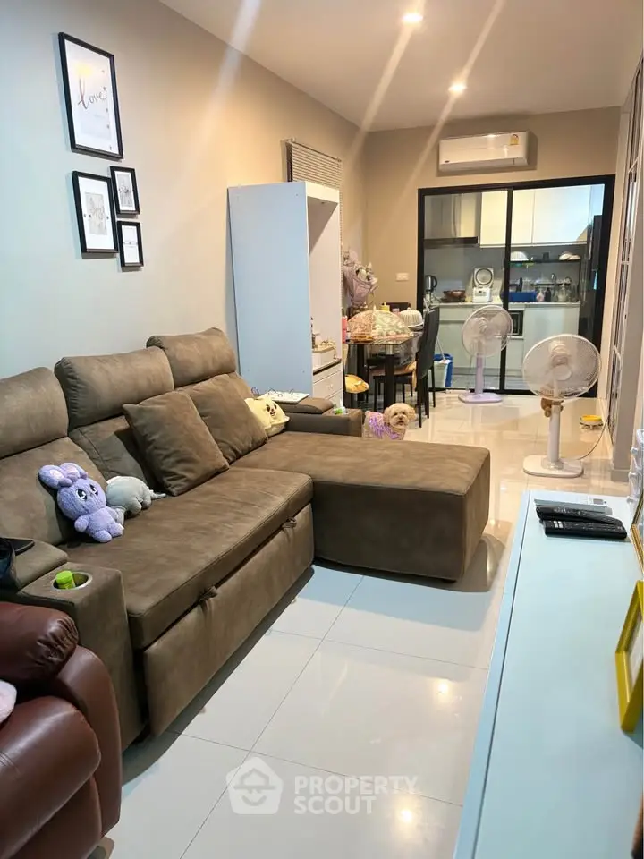 Cozy living room with plush sofa and modern kitchen in open layout apartment.