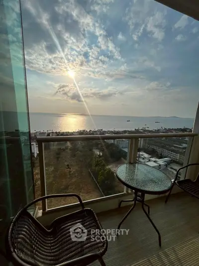 Stunning ocean view from a high-rise balcony with seating area, perfect for relaxation.