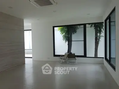 Spacious modern living room with large windows and minimalist design.