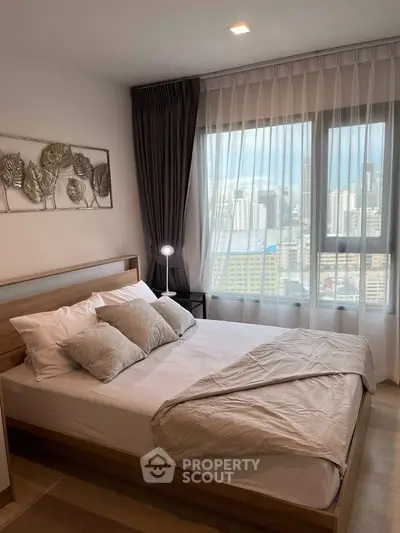 Modern bedroom with city view, featuring elegant decor and large window for natural light.