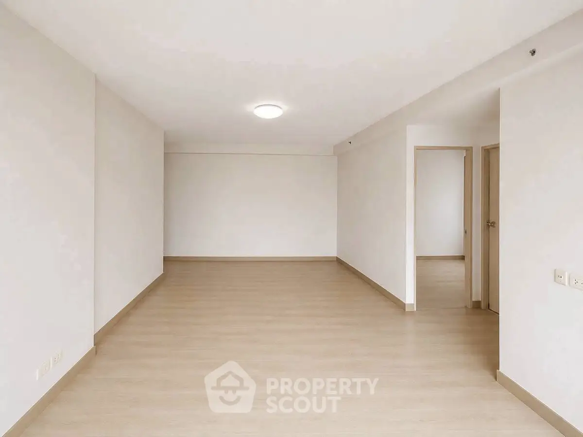 Spacious empty living room with light wood flooring and neutral walls, ideal for customization.