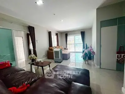 Spacious living room with modern leather sofa and large windows for natural light.