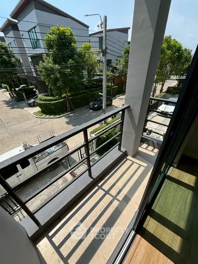 Charming balcony view in modern residential area with lush greenery and street view.