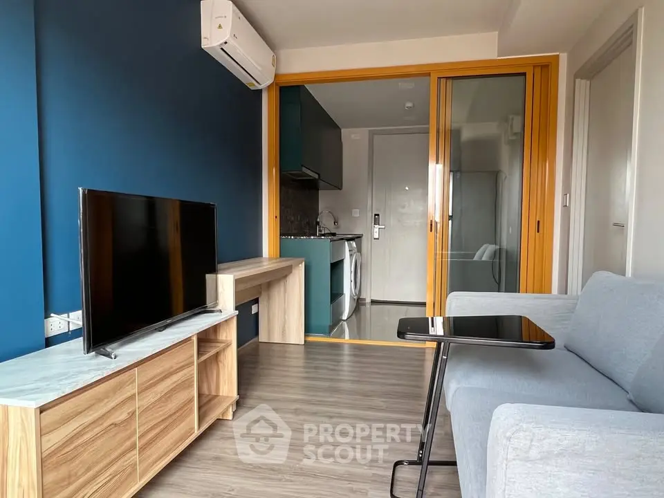 Modern living room with sleek furniture and glass partition to kitchen