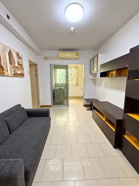 Modern living room with sleek furniture and tiled flooring, featuring a cozy sofa and stylish shelving.