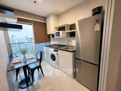 Modern kitchen with city view, featuring stainless steel appliances and dining area in a high-rise apartment.