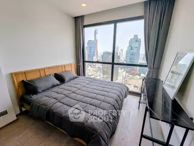Modern bedroom with stunning city view and large window, featuring sleek furnishings and natural light.