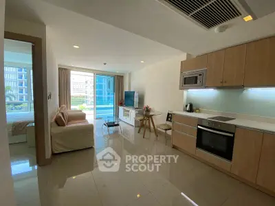 Modern open-plan living room with kitchen and pool view, featuring sleek furniture and natural light.