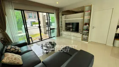 Spacious living room with modern decor and large glass doors opening to a garden view.