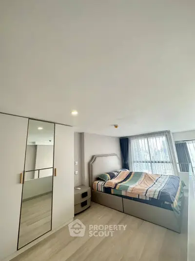 Spacious modern bedroom with large windows and stylish decor in a high-rise apartment.