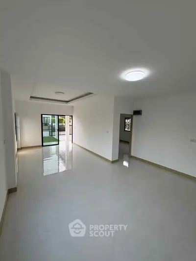 Spacious empty living room with large windows and modern lighting