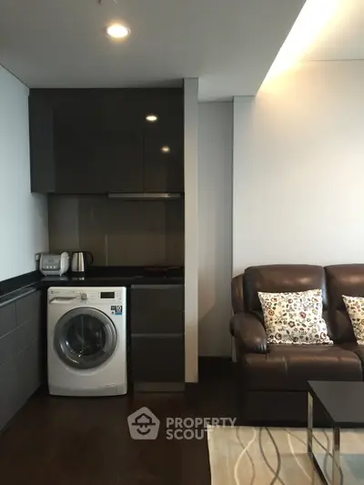Modern living room with sleek kitchen corner and washing machine, perfect for urban living.