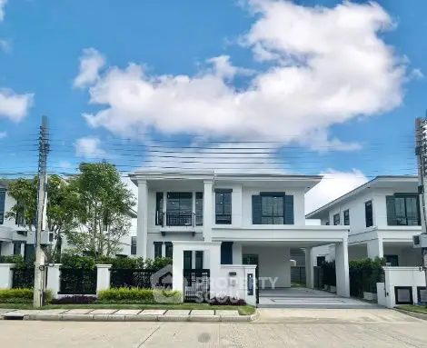Modern two-story white house with spacious driveway and lush greenery under a clear blue sky.