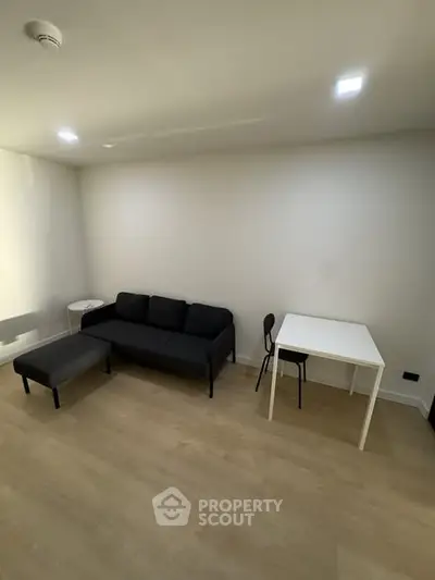 Modern minimalist living room with black sofa and white table, perfect for cozy urban living.