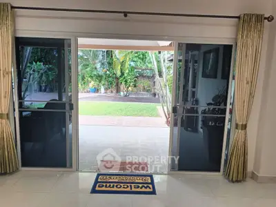 Spacious living room with sliding glass doors opening to a lush garden view, perfect for indoor-outdoor living.