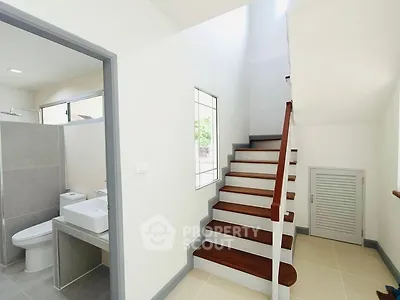 Modern staircase with adjacent bathroom in a bright, minimalist home interior.