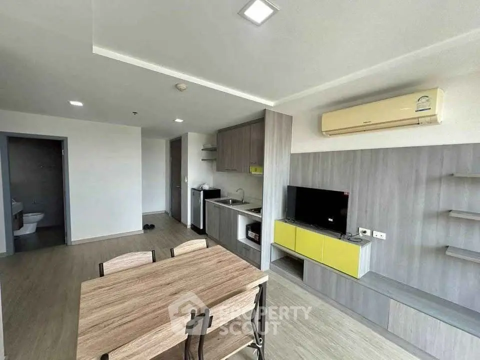 Modern open-plan living room with kitchen and dining area, featuring sleek design and natural light.