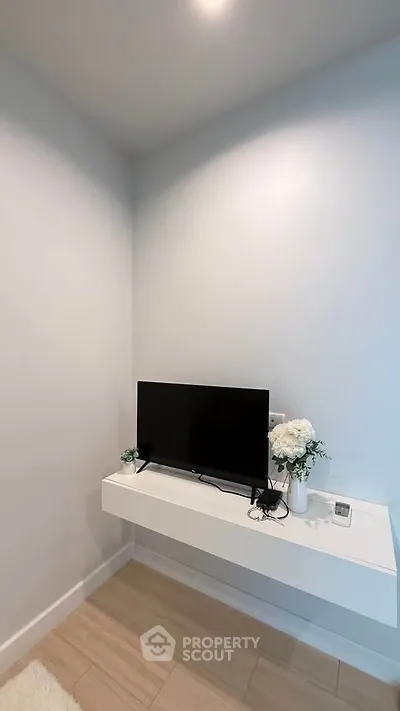 Modern minimalist living room corner with mounted TV and floral decor