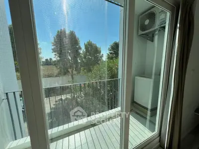 Charming balcony view with lush greenery and outdoor air conditioning unit, perfect for relaxation.