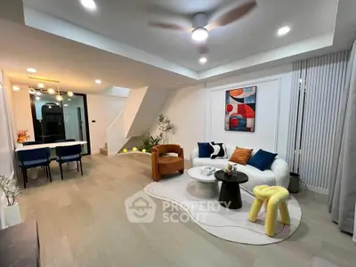 Modern living room with stylish decor and open dining area, featuring contemporary furniture and art.