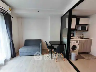 Modern studio apartment with open layout, featuring a cozy living area and compact kitchen with washing machine.