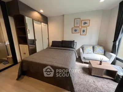 Cozy bedroom with modern decor and natural light, featuring a comfortable bed and stylish seating area.