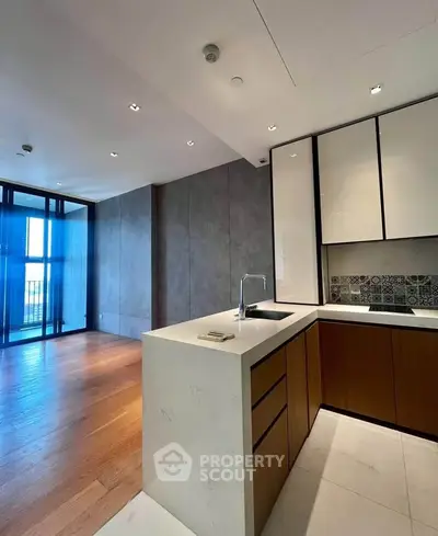 Modern open-layout kitchen with sleek design and wooden flooring, featuring a stylish backsplash and ample natural light.