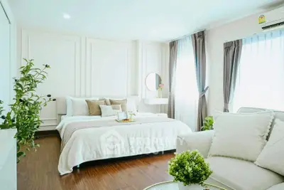 Luxurious bedroom with elegant decor and natural light, featuring cozy seating and stylish furnishings.