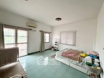 Spacious bedroom with large windows and minimalist decor, offering ample natural light and serene ambiance.