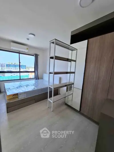 Modern bedroom with large window and stylish shelving unit, offering a bright and airy atmosphere.