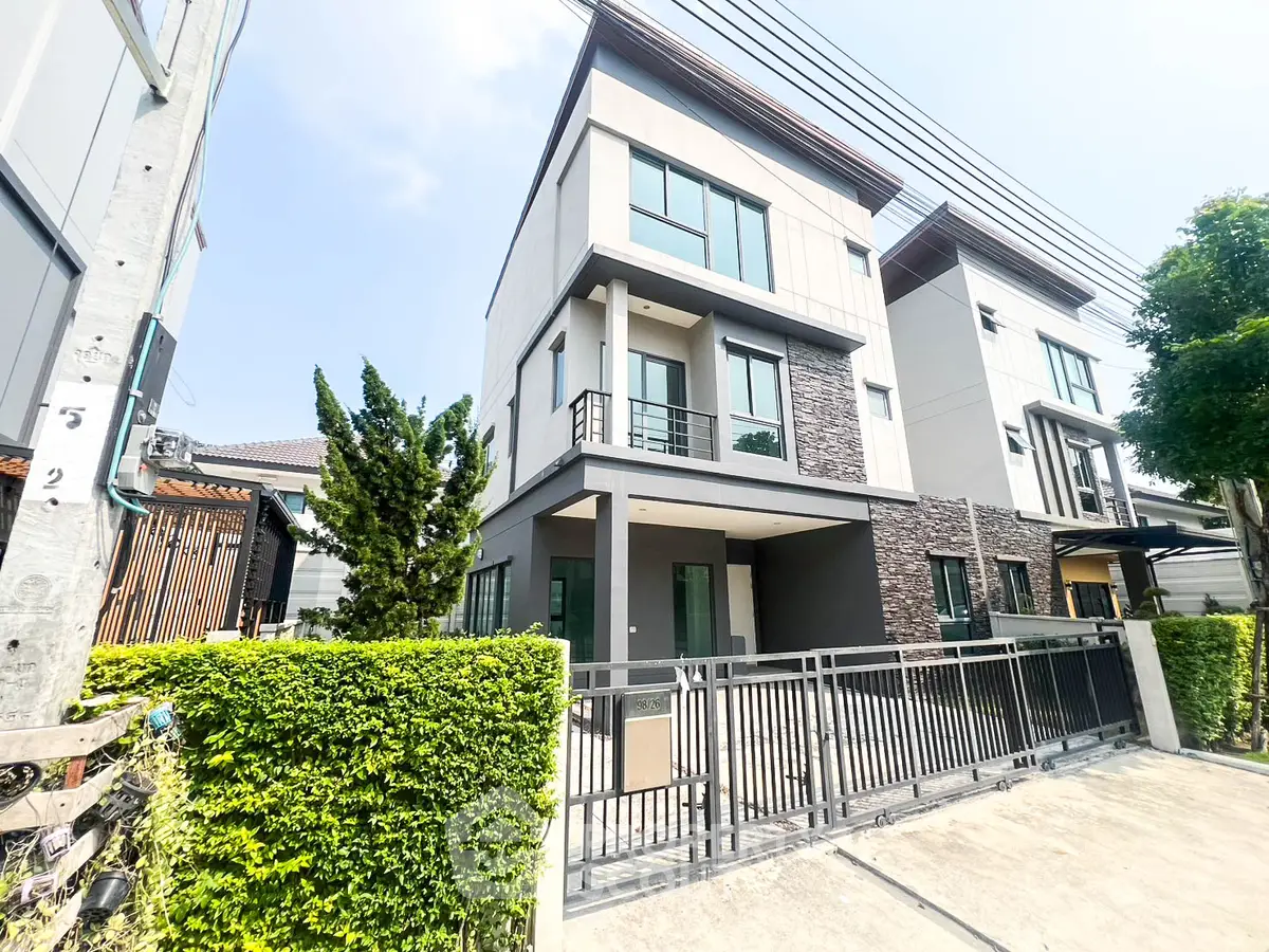 Modern three-story townhouse with sleek design and gated entrance in a suburban neighborhood.