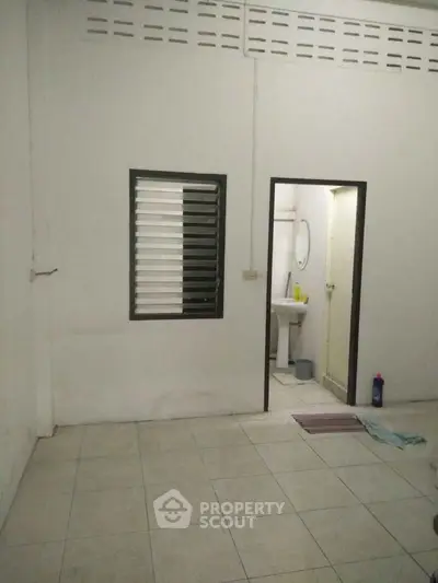 Simple bathroom with tiled floor and basic fixtures in a minimalist design.