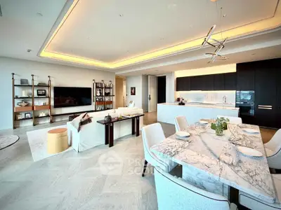 Luxurious open-plan living room with modern kitchen and elegant dining area, featuring stylish lighting and decor.