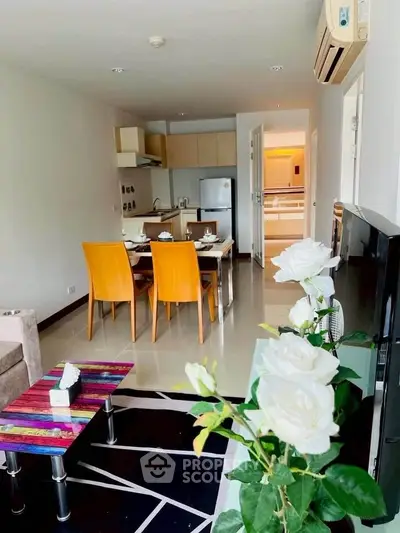 Modern open-layout living room with dining area and kitchen, featuring stylish furniture and bright decor.