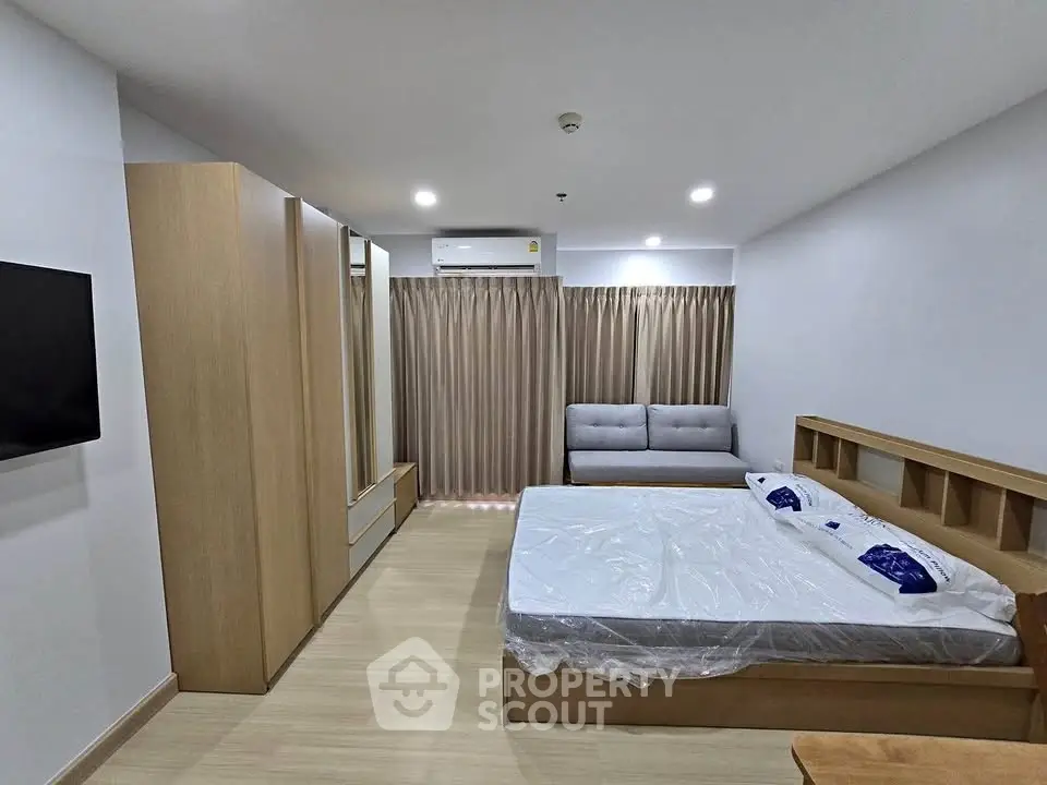 Spacious modern bedroom with wooden flooring and stylish furniture in a cozy apartment.
