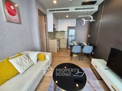 Modern open-layout living room with kitchen, featuring stylish furniture and contemporary lighting.