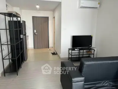 Modern living room with sleek black furniture and open layout, featuring a TV and air conditioning.